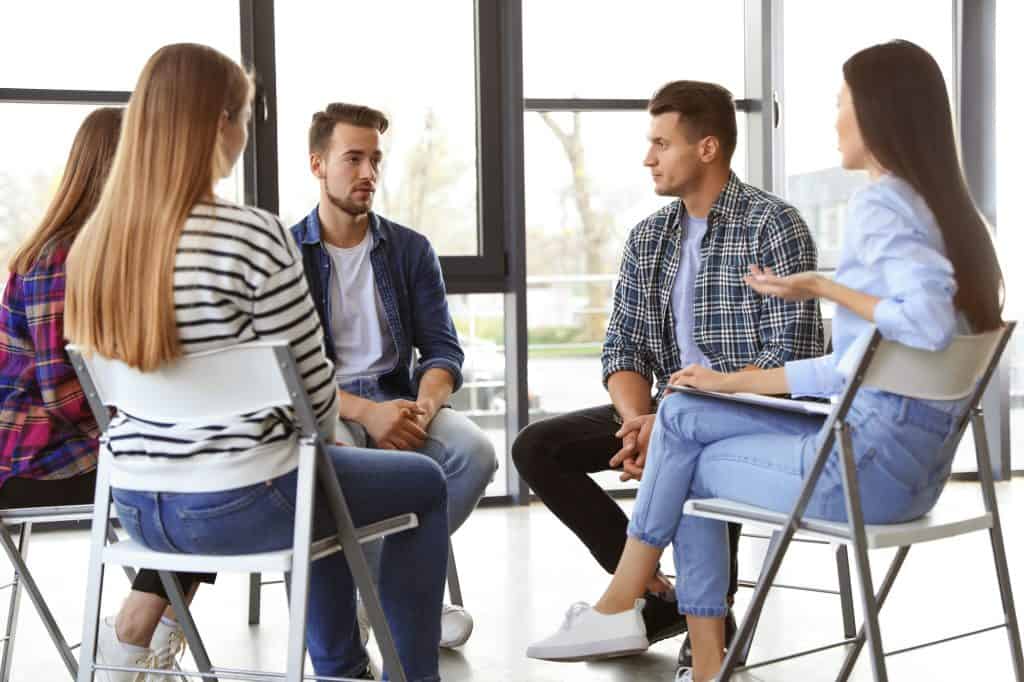Psychotherapist working with patients in group therapy session indoors