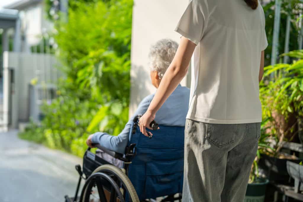 Caregiver help and care Asian senior or elderly old lady woman patient sitting on wheelchair to ramp in nursing hospital, healthy strong medical concept.